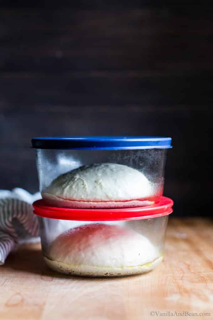 Pizza dough in two lidded glass containers stacked on top of each other after an overnight rest in the fridge.