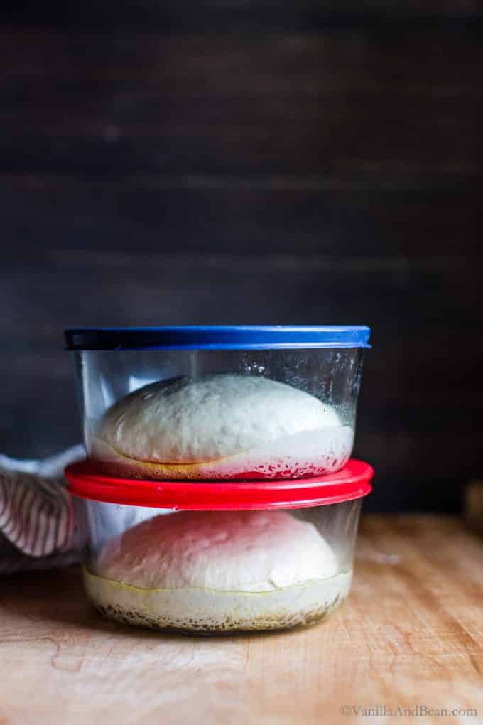 Pizza dough in two lidded glass containers stacked on top of each other after two and a half hours at room temperature.