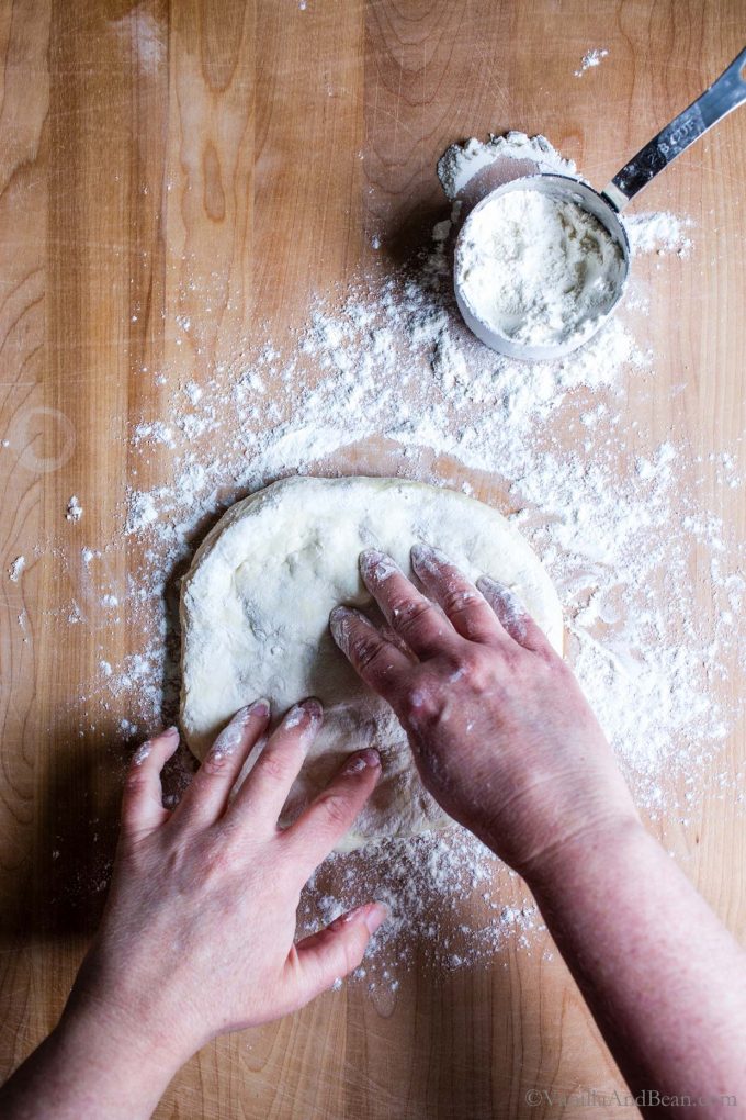 Shaping the pizza dough with two hands.
