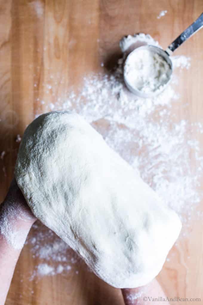 Shaping the pizza dough with the backs of floured hands.