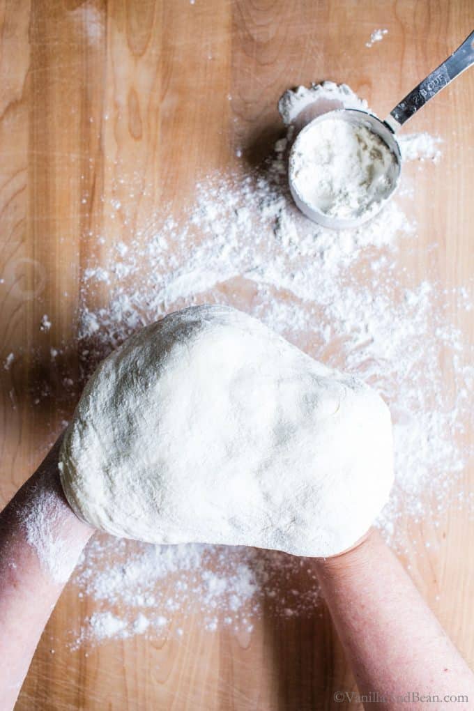 Shaping the pizza dough with the backs of floured hands.