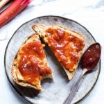 Peanut butter and rhubarb jam on toast, on a plate with a jam filled spon.