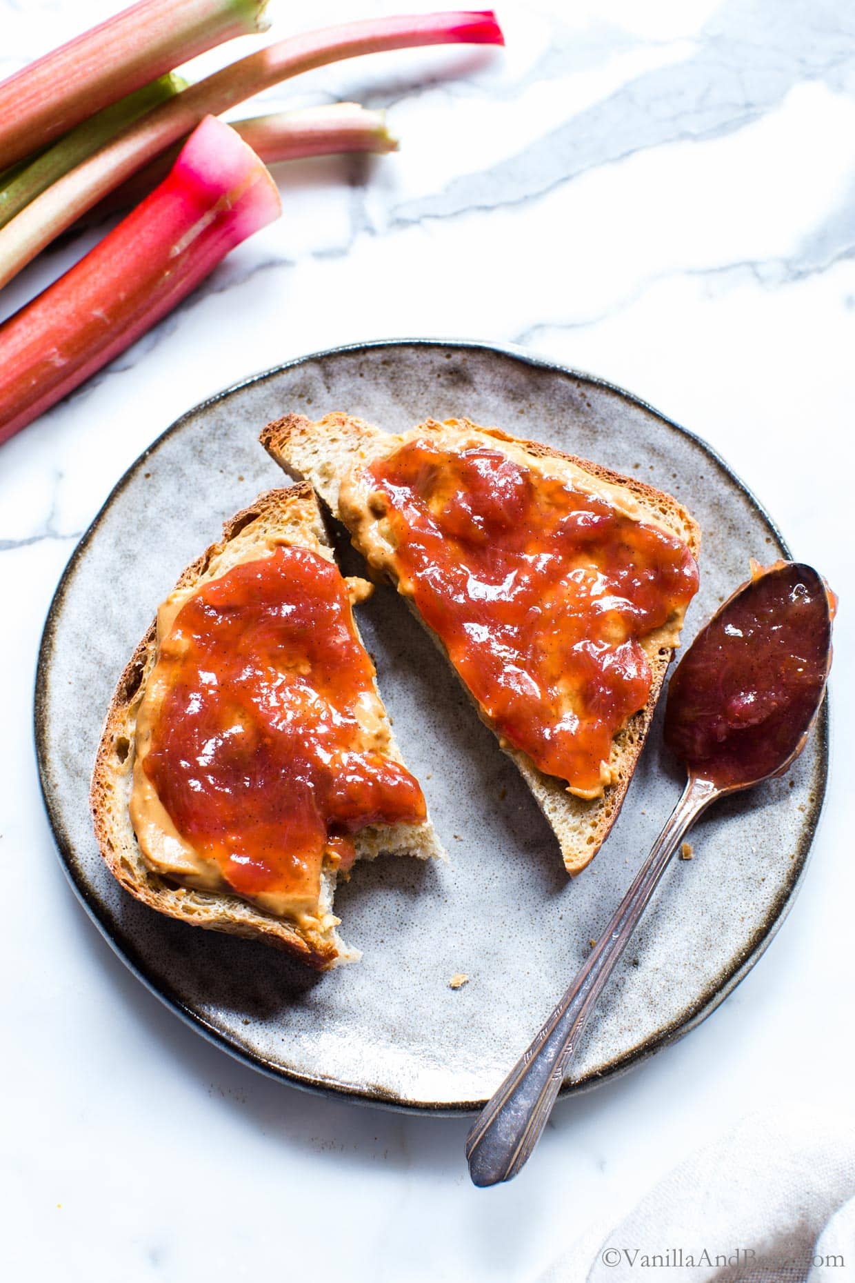 Peanut butter and rhubarb jam on toast, on a plate with a jam filled spon.