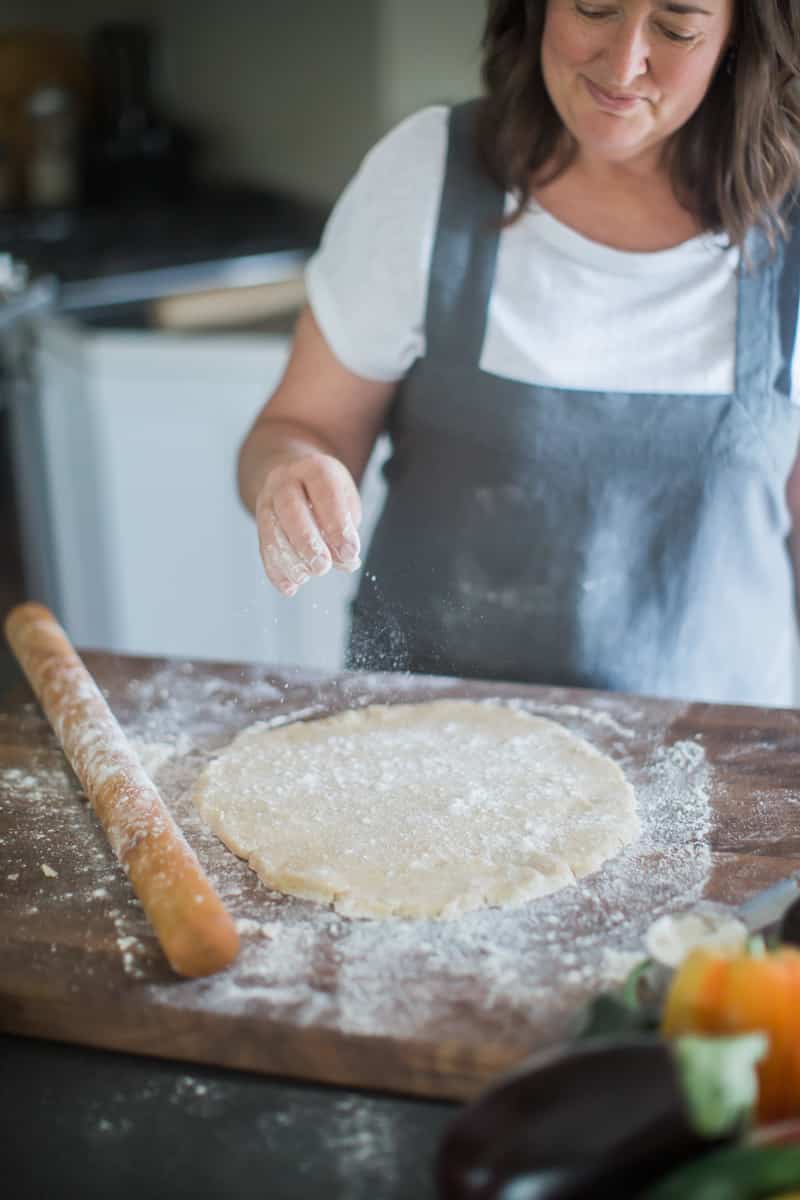 Traci sprinkling flour over a disk of pastry.