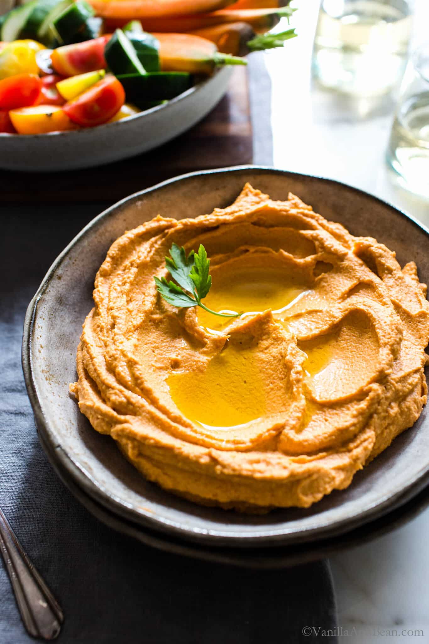 Red Pepper Hummus Recipe in a bowl with olive oil drizzled on top.