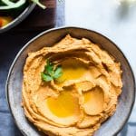 Roasted Red Pepper Hummus in a bowl with olive oil drizzled on top.