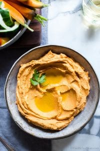 Roasted Red Pepper Hummus in a bowl with olive oil drizzled on top.