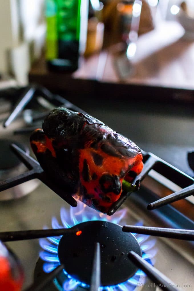 Roasting a red bell pepper on a stove top flame. 