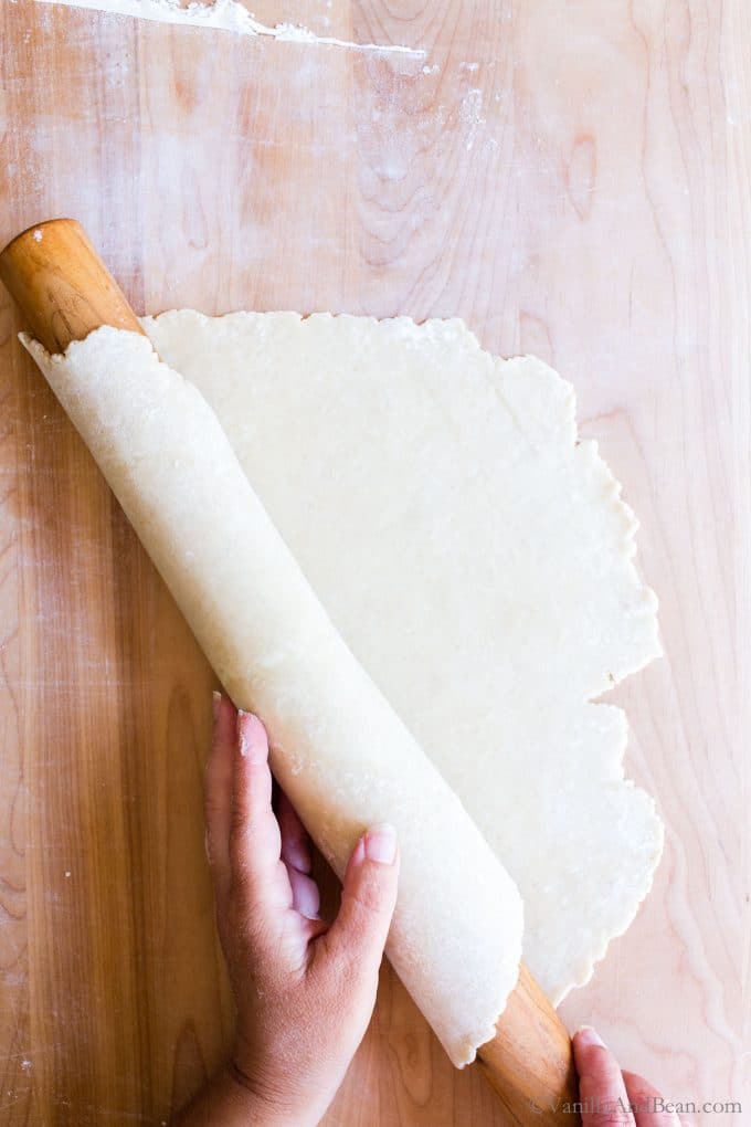 Rolling the dough up on a rolling pin. 
