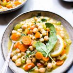 Vegetarian Noodle Soup with chickpeas in a bowl garnished with lemon and spinach.