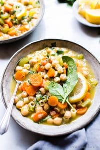Vegetarian Noodle Soup with chickpeas in a bowl garnished with lemon and spinach.