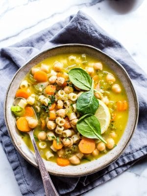 Vegetarian Noodle Soup with Chickpeas in a bowl garnished with lemon and spinach.