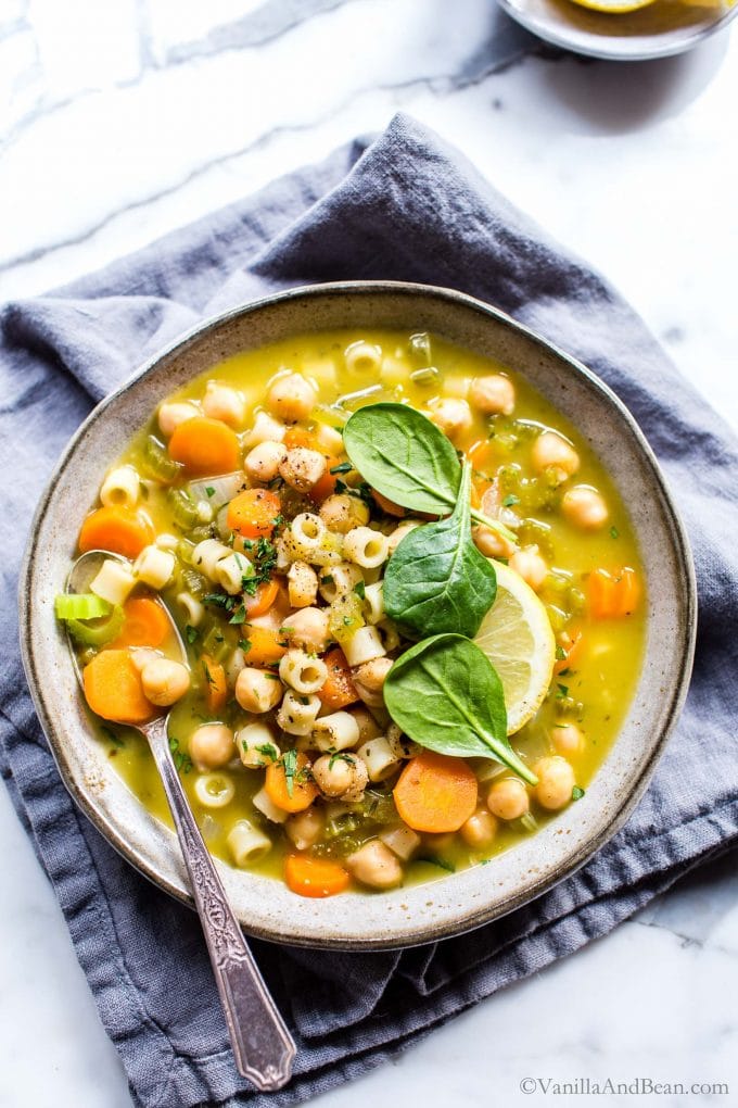 Vegetarian Noodle Soup with Chickpeas in a bowl garnished with lemon and spinach.