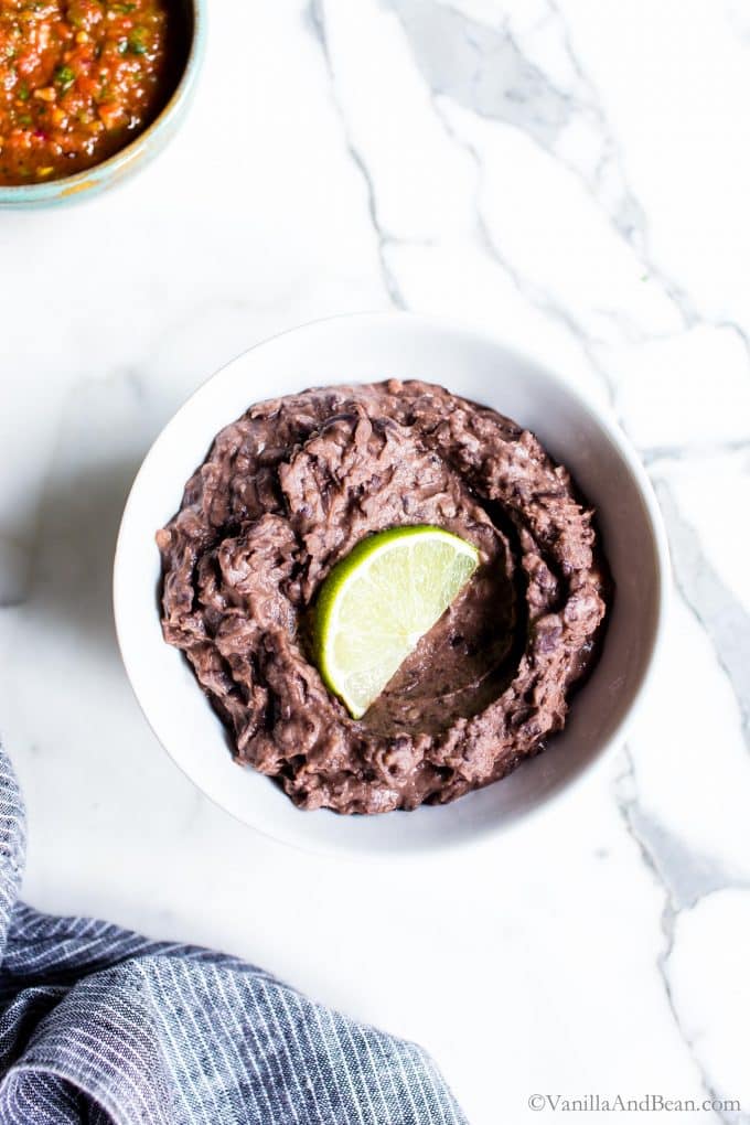 Vegetarian Refried Black Beans in a bowl with a lime wedge.