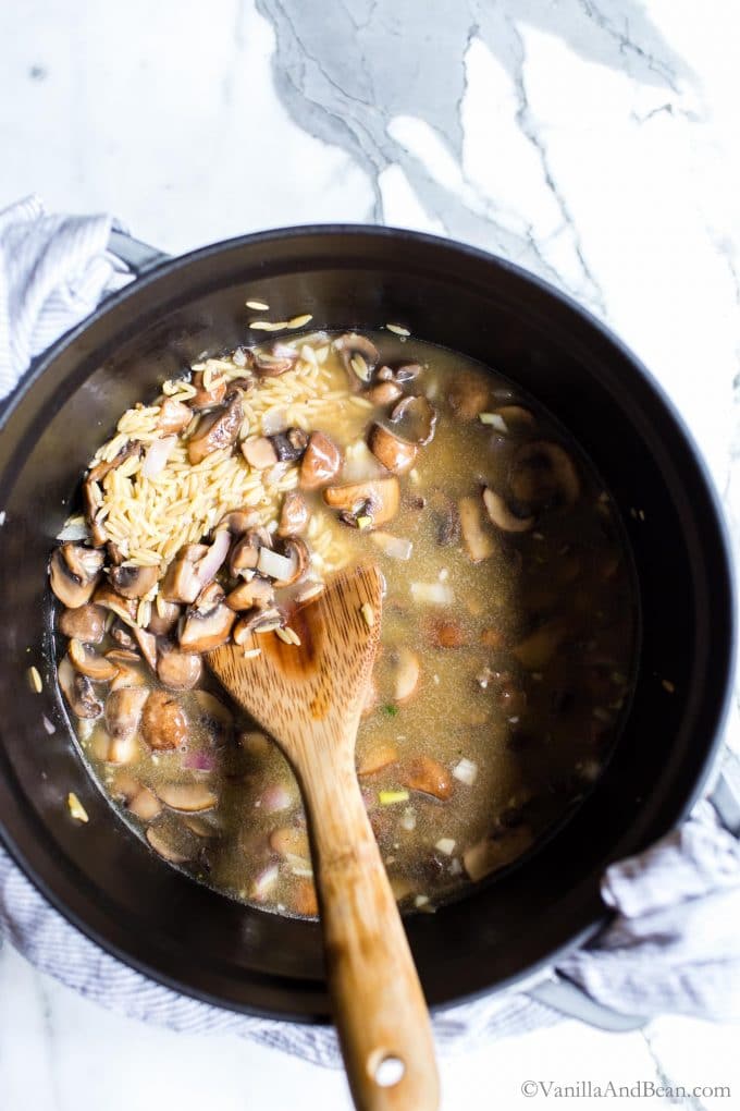 Mushroom orzo recipe in a Dutch oven with a spoon. 