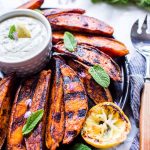 Grilled Sweet Potato Wedges on a plate with sauce and garnished with mint.