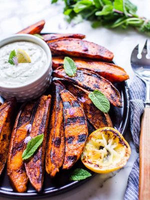 Grilled Sweet Potato Wedges on a plate with sauce and garnished with mint.
