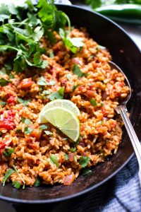 Mexican Rice Recipe Vegetarian in a pan, garnished with lime and cilantro.