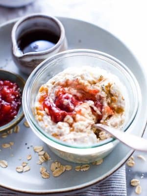 Overnight oats with peanut butter and jam in a glass jar with a spoon in it.