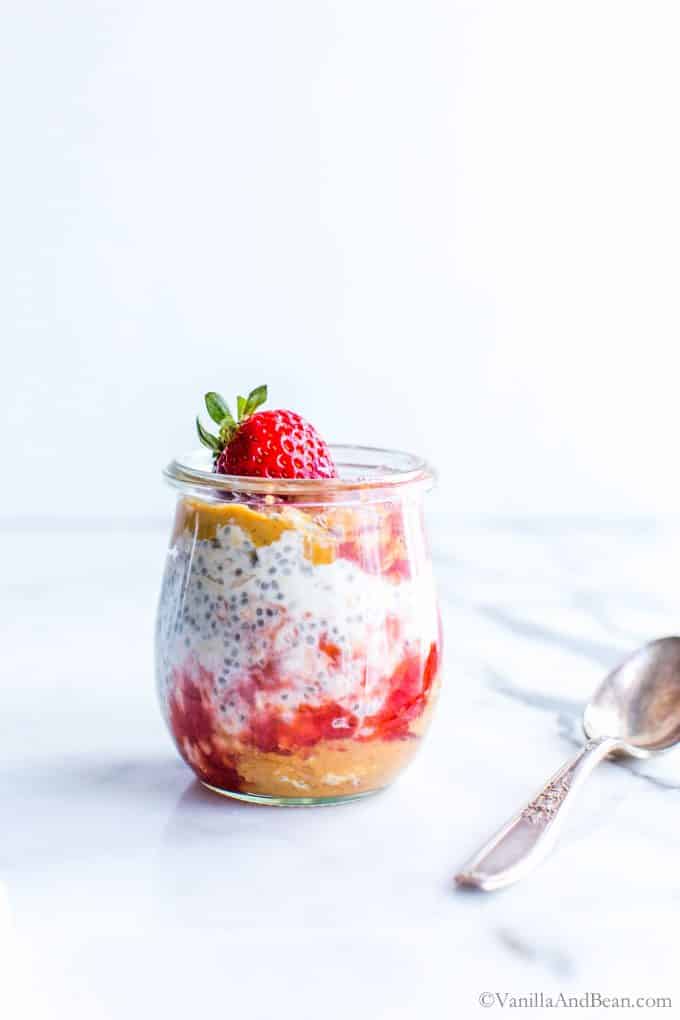 Dairy Free Peanut Butter Overnight Oats with strawberry jam and chia seeds in a small Jar ready to eat.