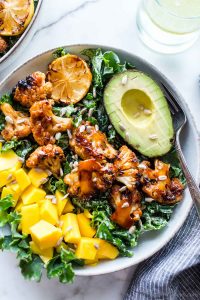 Grilled BBQ Cauliflower Bowl with mango and avocado, slathered with BBQ sauce and garnished with sunflower seeds.