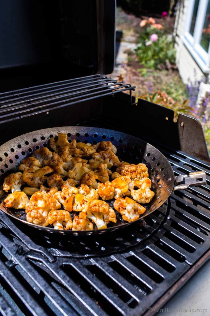 Barbeque Cauliflower pieces in a grill pan on the gas grill.