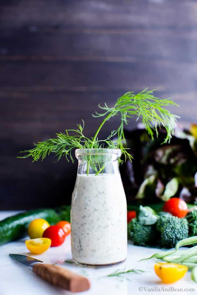 Dairy free ranch dressing in a bottle with sprigs of dill coming out of the top.