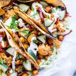 Closeup of Harissa Cauliflower Tacos Recipe garnished with sour cream and cucumbers.