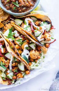 Closeup of Harissa Cauliflower Tacos Recipe garnished with sour cream and cucumbers.