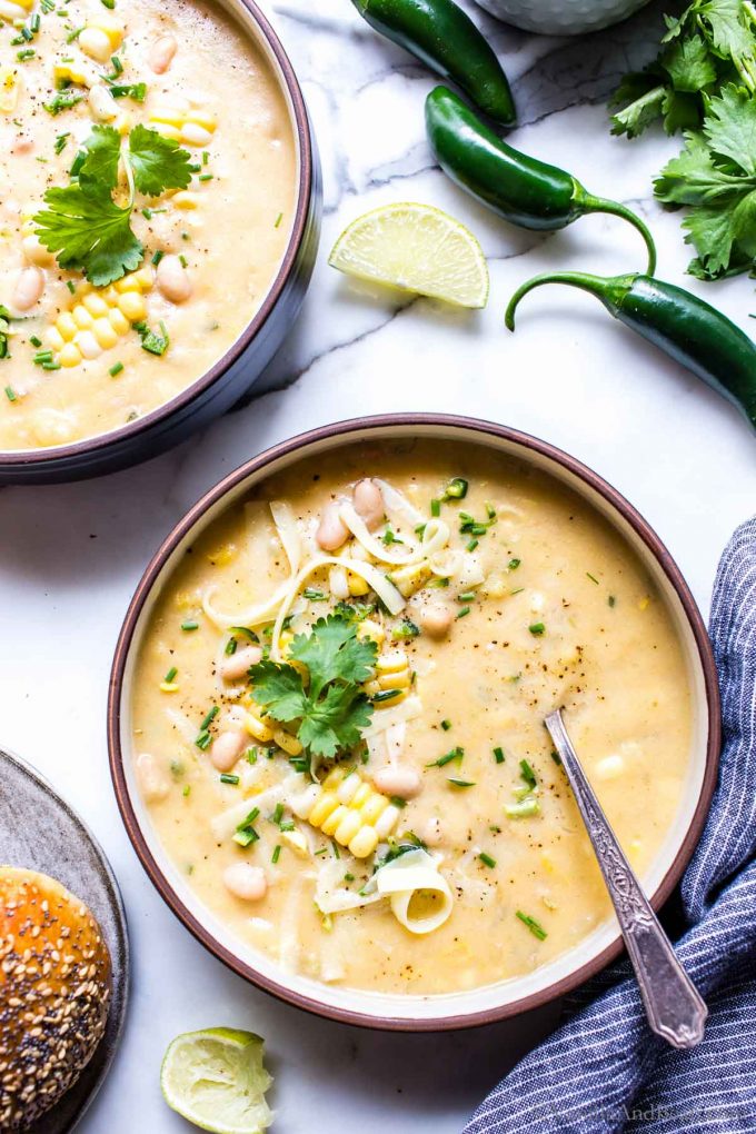 Potato Corn Chowder Vegetarian in a bowl garnished with cheese, cilantro and lime. 