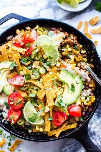 One Pan Mexican Quinoa Recipe Vegetarian in a skillet garnished with jalapenos and avocados.