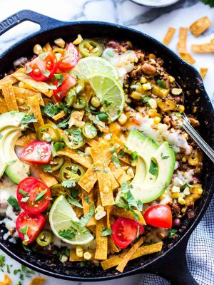 One Pan Mexican Quinoa Recipe Vegetarian in a skillet garnished with jalapenos and avocados.