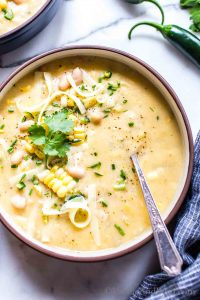 Potato Corn Chowder Vegetarian in a bowl garnished with cheese, cilantro and lime.