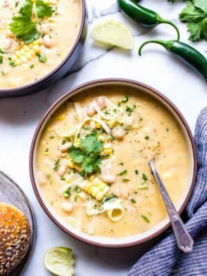 Potato Corn Chowder Vegetarian in a bowl garnished with cheese, cilantro and lime.