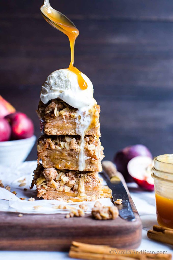 Apple Crisp Bars Recipe with ice cream on top and caramel sauce drizzled over the top.