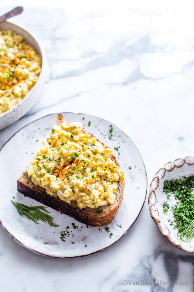 Deviled Egg Salad on a slice of bread garnished with chives and dill.