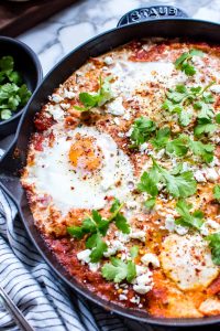 Closeup of a a skillet of eggs Shakshuka garnished with cilantro and feta.