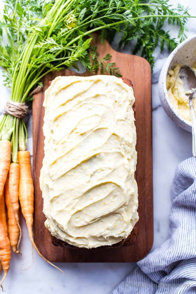 Carrot Cake Loaf Recipe on a cutting board iced with cream cheese icing ready for sharing.