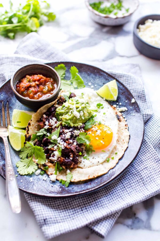 Huevos rancheros with a fried egg, guacamole and beans on a plate.
