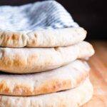 Four Sourdough Pitas stacked and wrapped in a tea towel.