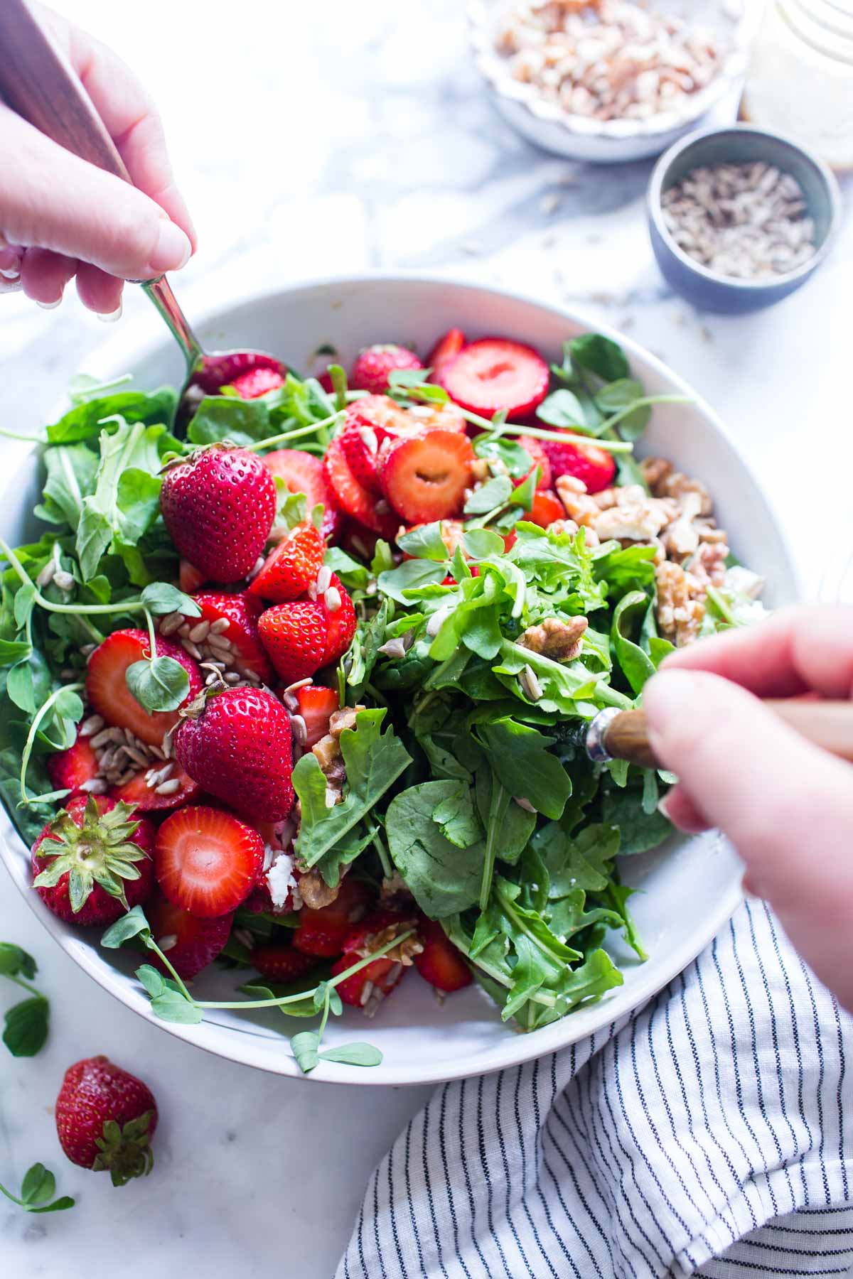 Tossing a salad with arugula strawberries and goat cheese.