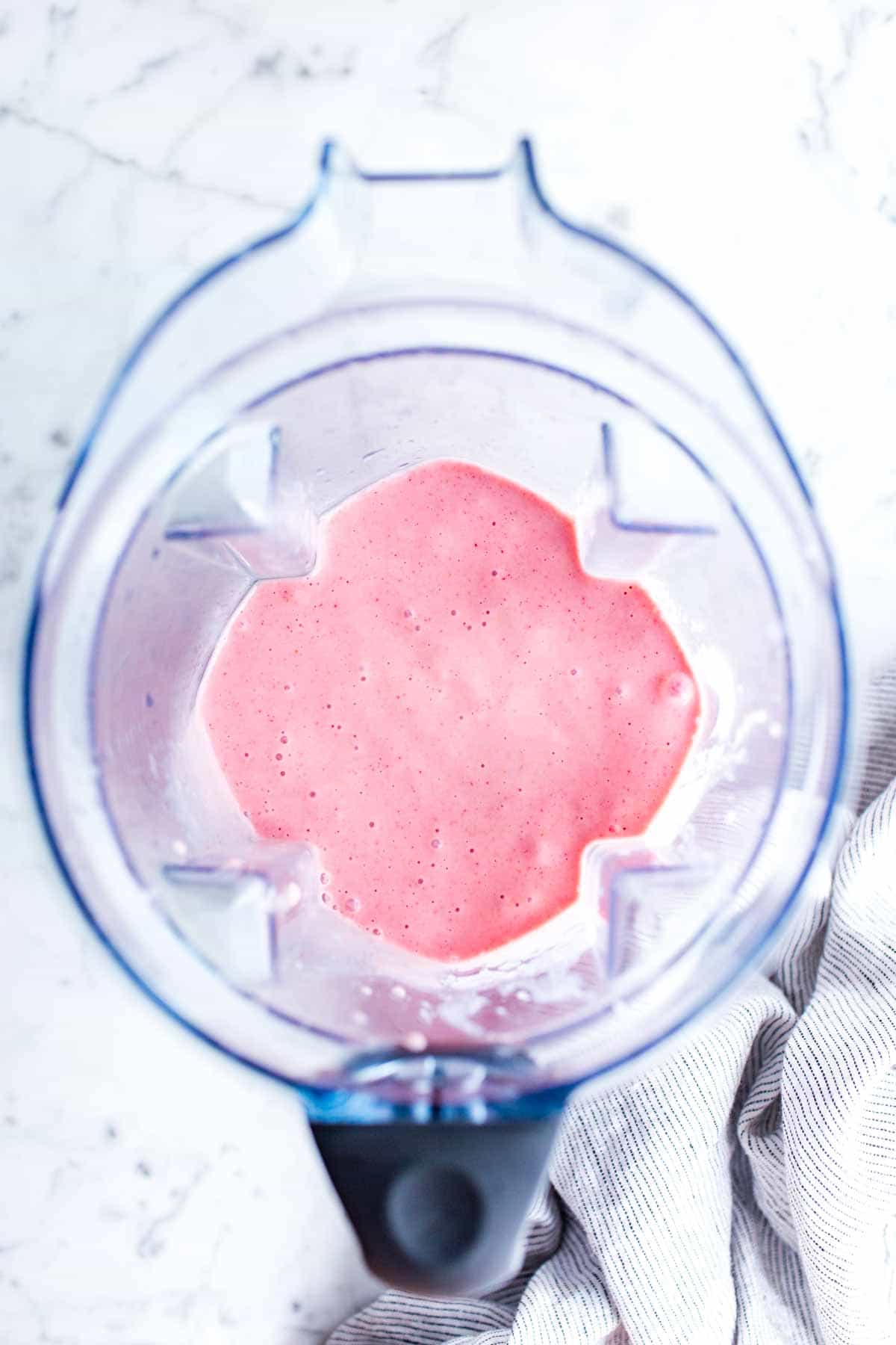 Blended strawberry banana milk shake in a blender pitcher.
