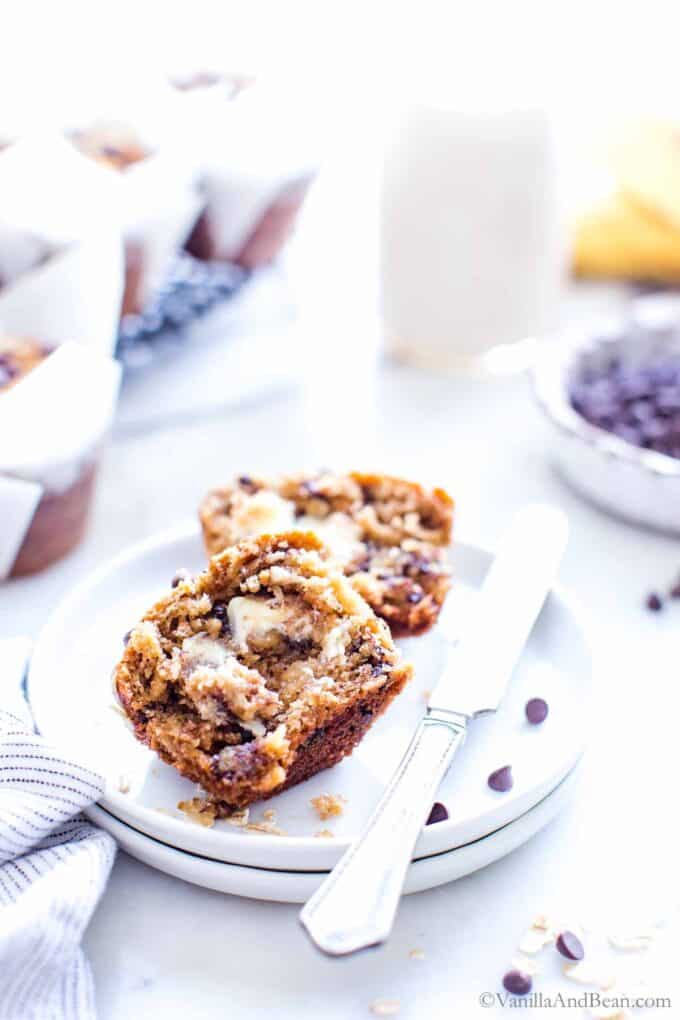 healthy banana oatmeal chocolate chip muffins on a plate with butter spread on each half.