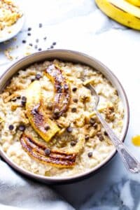 Creamy oatmeal in a bowl with fried bananas, chocolate chips and