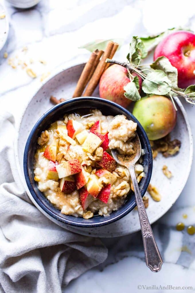 Creamy oats in a bowl with diced apples, walnuts and maple syrup.