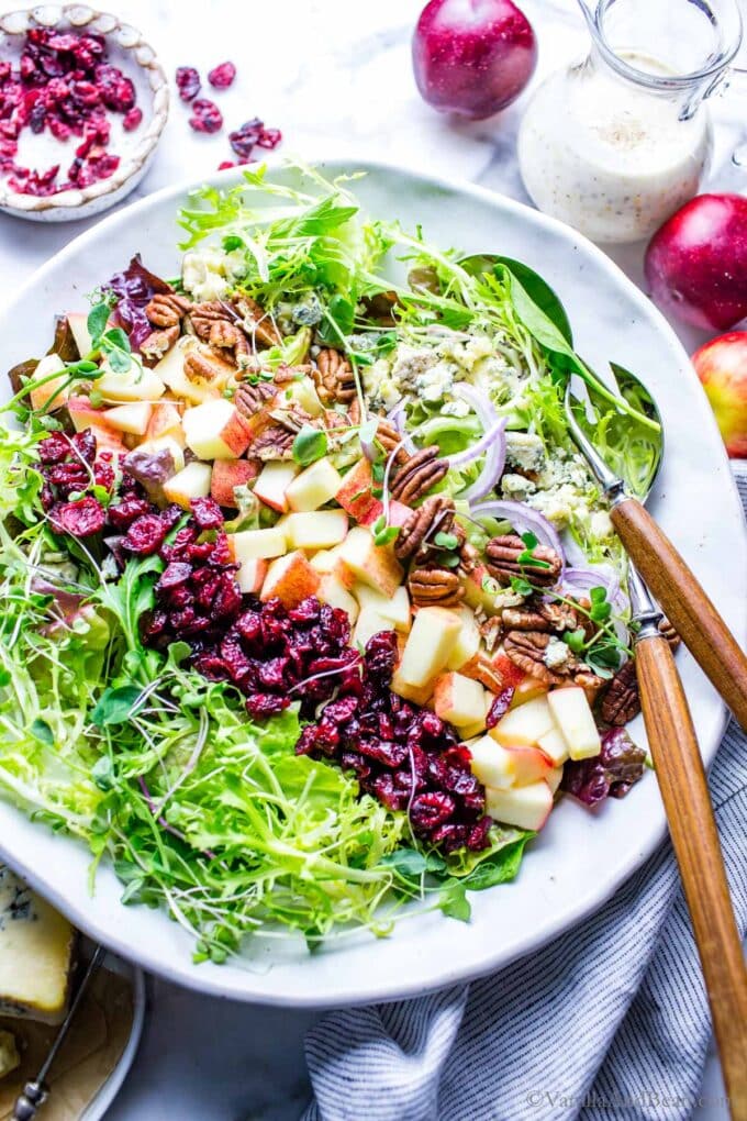 Apple and cranberry salad in a big serving bowl with salad spoons on the side ready for sharing. 