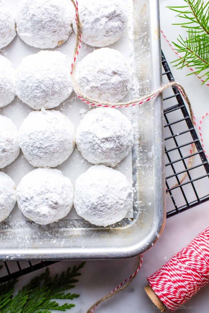 Melt in your mouth Italian wedding cookies on a sheet pan with bakers twine rolled out.