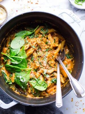 Creamy Vegetarian Pasta in a Dutch oven with tomato mascarpone sauce in a Dutch oven garnished with spinach, basil and Parmesan cheese.