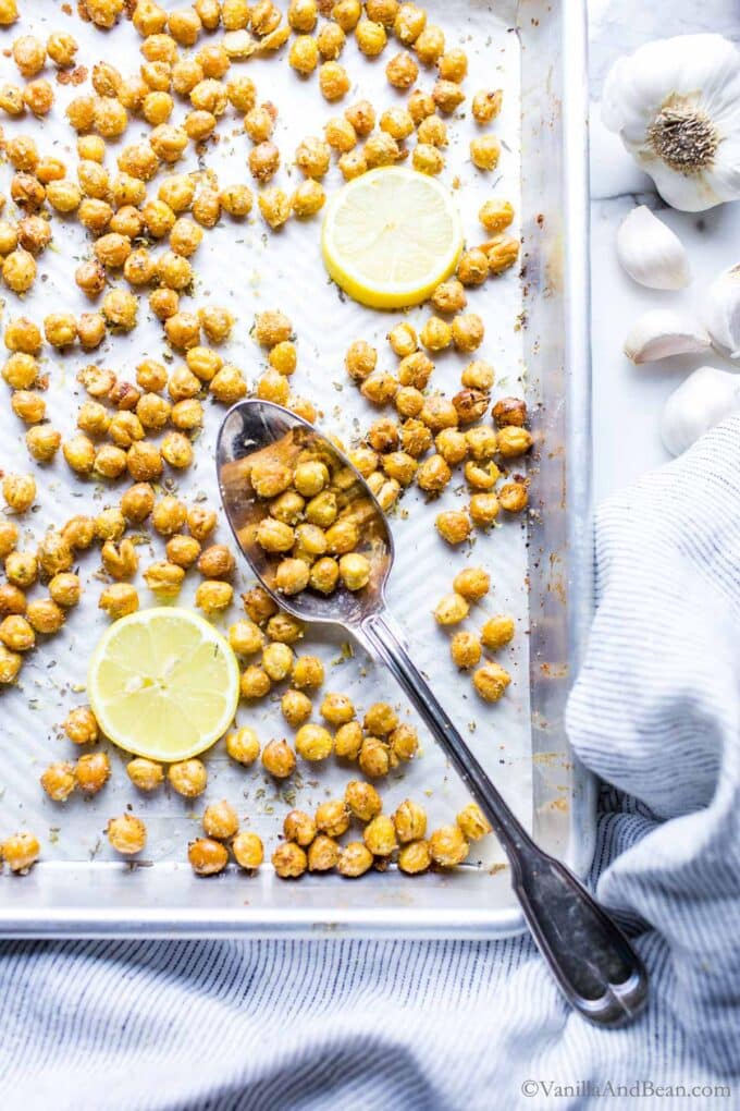 Crispy chickpea croutons on a sheet pan in a spoon with a lemon slice on the side.