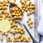 Crispy chickpea croutons on a sheet pan in a spoon with a lemon slice on the side.